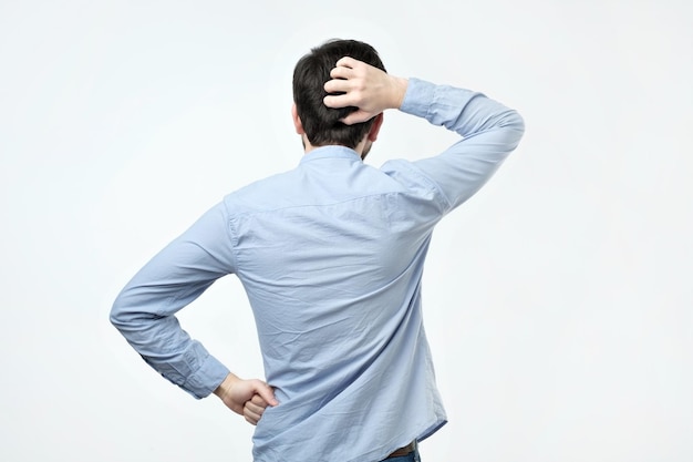 studio shoot of young man in blue shirt standing back to the camera