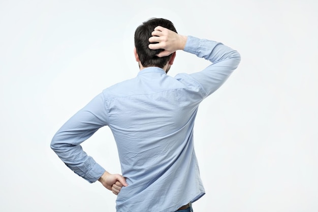 Studio shoot of young man in blue shirt standing back to the camera