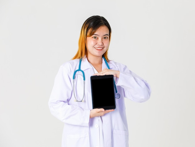 Studio shot of Asian successful professional confident female doctor in lab coat uniform hanging stethoscope around neck take coffee break standing smiling holding table on white background.