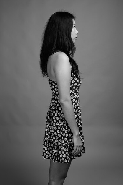 Studio shot of Asian woman wearing dress against gray background in black and white