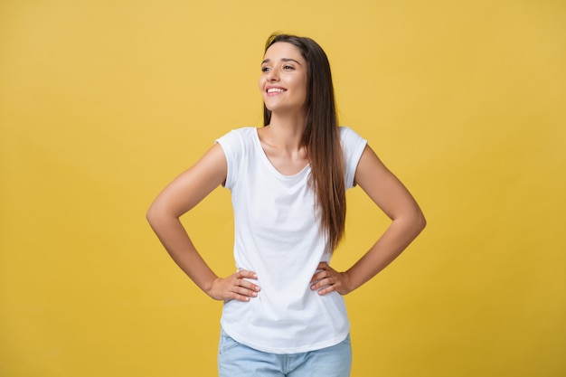 Studio shot of attractive self confident young female in great mood feeling happy, holding hands on her slender waist and looking at camera with radiant smile.