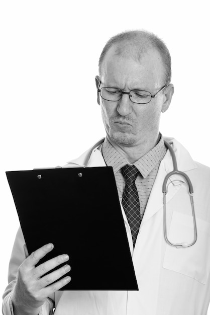 Studio shot of bald man doctor with beard stubble isolated against white background in black and white