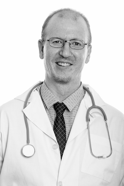 Studio shot of bald man doctor with beard stubble isolated against white background in black and white