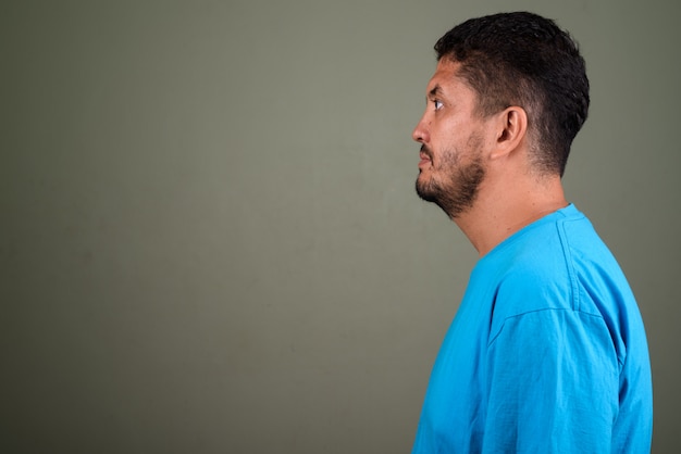 Studio shot of bearded man wearing blue shirt against colored