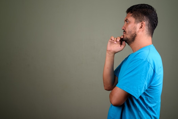 Studio shot of bearded man wearing blue shirt against colored