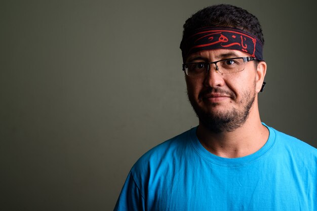 Studio shot of bearded man wearing blue shirt against colored