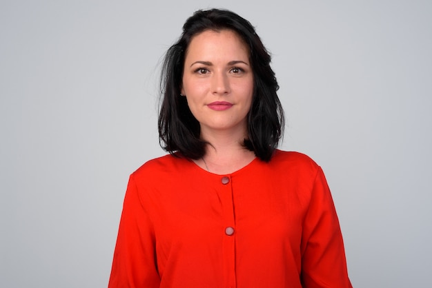 Studio shot of beautiful woman wearing red dress against white