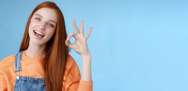 Studio shot carefree happy attractive european redhead girl show okay ok sign smiling white teeth