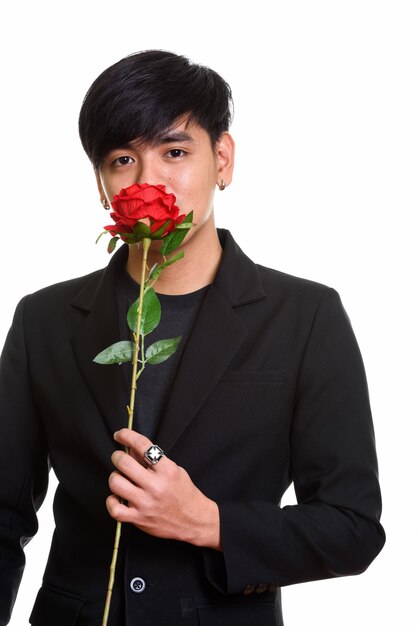 Studio shot of cool handsome Asian man smelling red roses