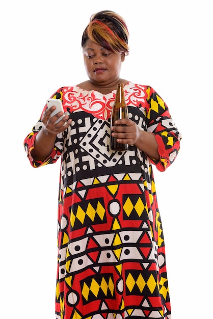 Студийный снимок толстой черной женщины, стоящей и использующей мобильный телефон