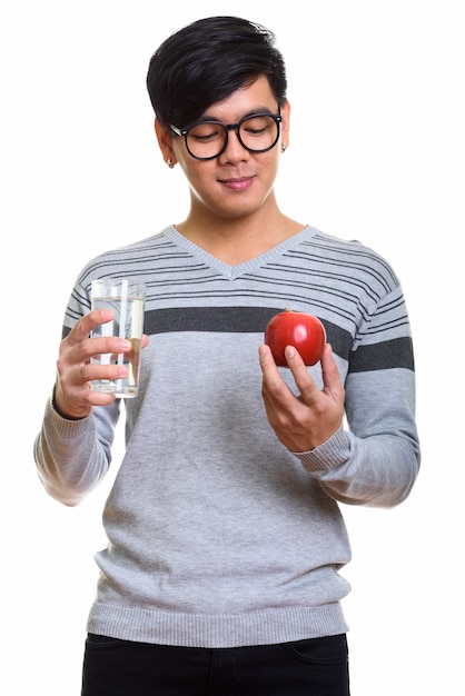 Studio shot of handsome Asian man holding glass of water and loo