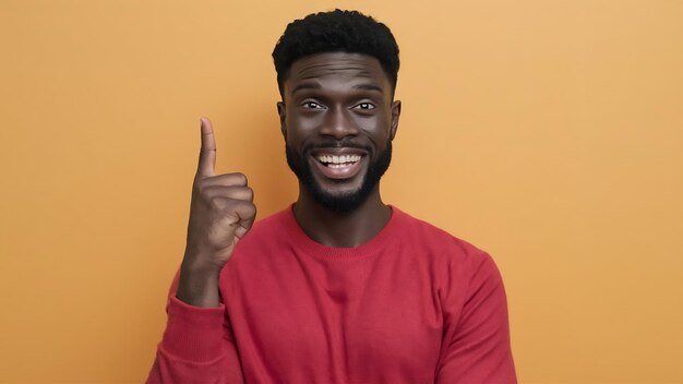 Studio shot of handsome cheerful dark skinned man with toothy smile indicates with thumb aside