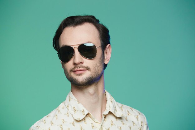 Studio shot of handsome man wearing sunglasses over green background