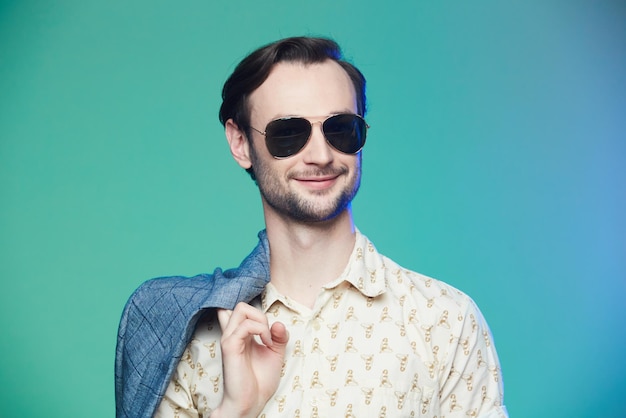 Studio shot of handsome man wearing sunglasses over green background