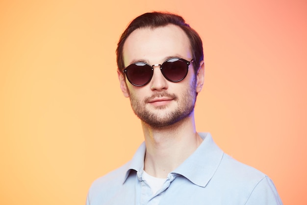 Studio shot of handsome man wearing sunglasses over orange background