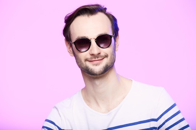 Studio shot of handsome man wearing sunglasses over pink background