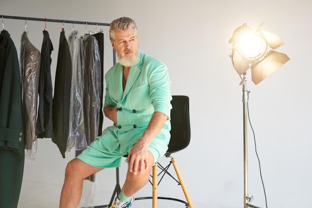 Studio shot of handsome mature man with beard wearing stylish colorful outfit looking aside while