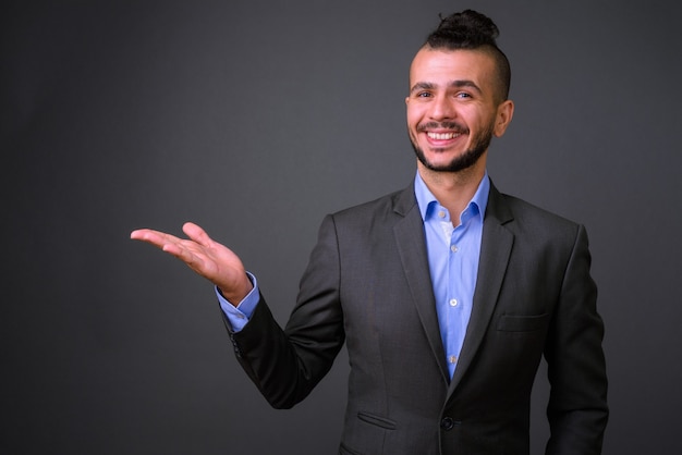 Studio shot di bel uomo d'affari turco che indossa tuta contro uno sfondo grigio