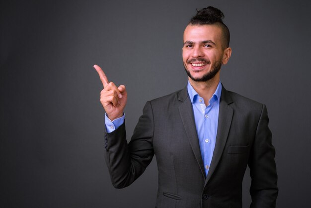 Studio shot di bel uomo d'affari turco che indossa tuta contro uno sfondo grigio