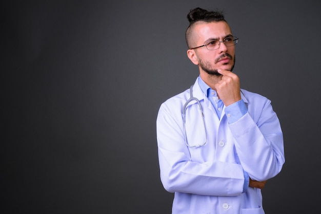 Studio shot of handsome Turkish man doctor against gray background