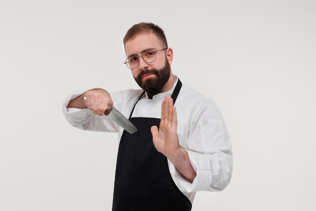 흰 바탕에 날카로운 칼을 들고 있는 행복한 수염을 기른 젊은 요리사의 스튜디오 샷