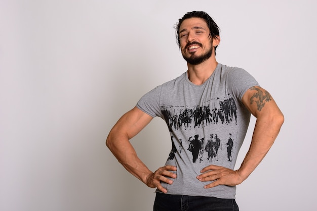 Studio shot of happy handsome muscular man smiling and posing wi