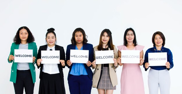 Studio shot of happy smile female officer staff in business wears hold variety fonts welcome letters paper sign show warm greeting to client customers or new colleagues on white background.