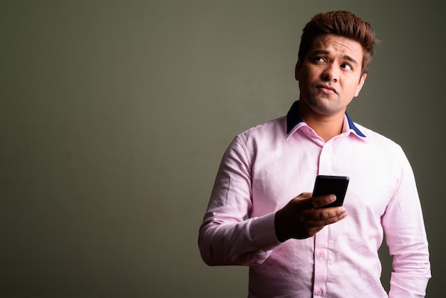 Studio shot of Indian businessman wearing pink shirt against colored background