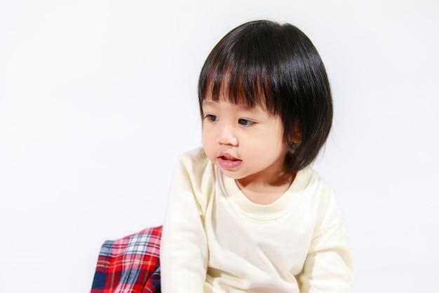 Studio shot of little cute short black hair Asian baby girl daughter model in casual plaid skirt sitting and smiling on white background