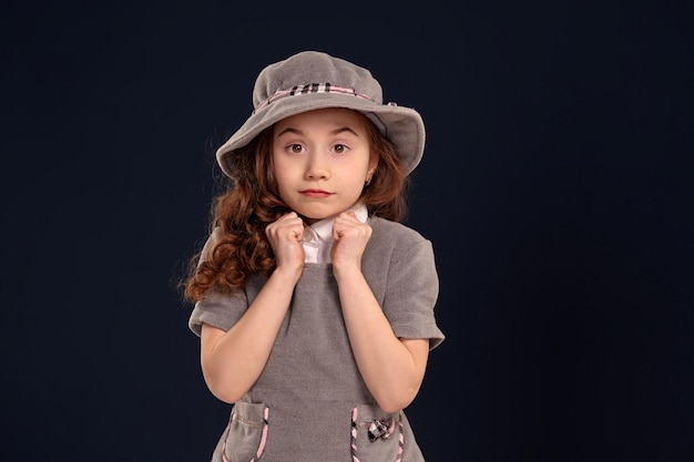 Studio shot of a lovely little kid with a long curly hair posing on a black background