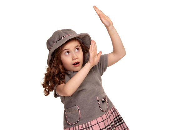 Studio shot of a lovely little kid with a long curly hair posing isolated on white background