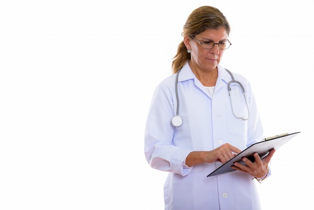 Studio shot of mature beautiful woman doctor reading on clipboard