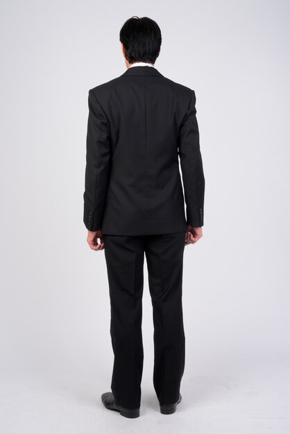 Studio shot of mature handsome businessman wearing tuxedo against white