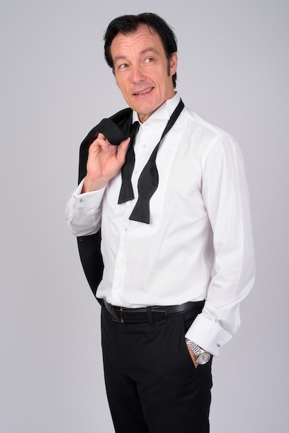 Studio shot of mature handsome businessman wearing tuxedo against white