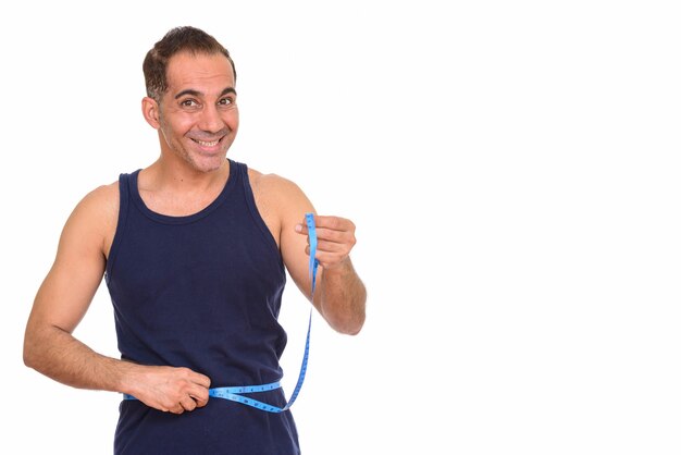 Studio shot of mature handsome Persian man ready for gym isolated against white background