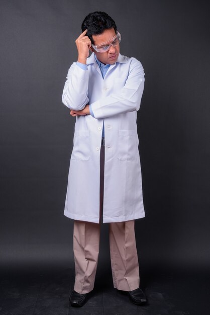 Studio shot of mature Indian man doctor against black background