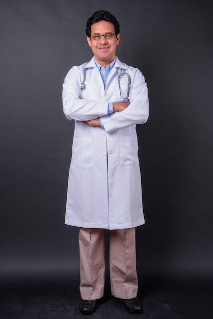 Studio shot of mature Indian man doctor against black background