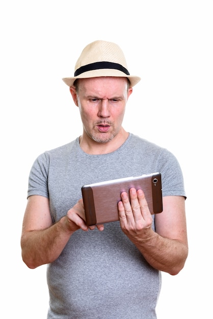 Студийный снимок зрелого мужчины, использующего цифровой планшет, выглядит смущенным