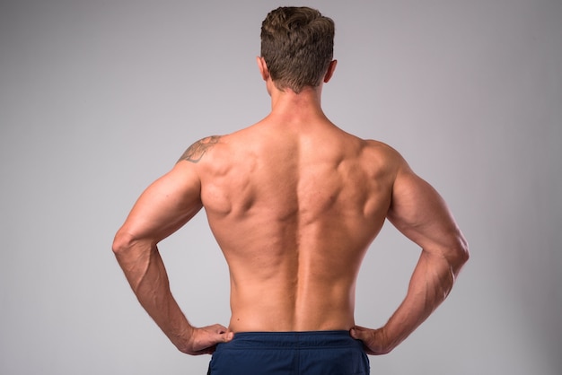 studio shot of muscular handsome bearded man shirtless against white