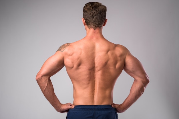 Studio shot of muscular handsome bearded man shirtless against white