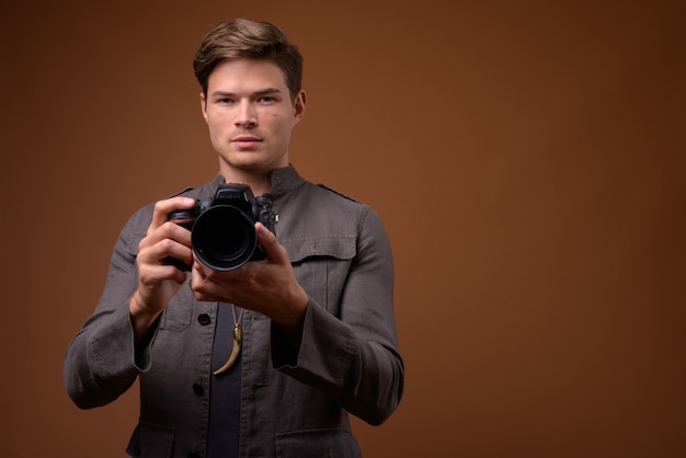 Фото Студийный снимок молодого красивого человека как фотографа с камерой