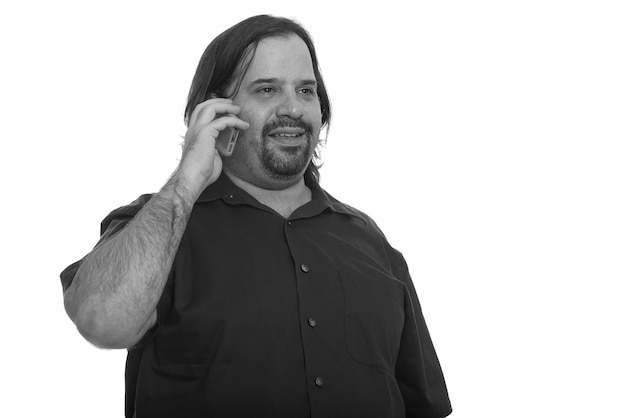 Studio shot of overweight bearded man isolated against white background in black and white