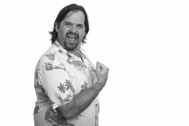 Studio shot of overweight bearded tourist man ready for vacation isolated against white background in black and white