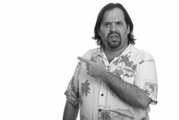 Studio shot of overweight bearded tourist man ready for vacation isolated against white background in black and white