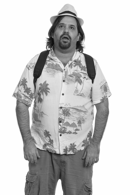 Studio shot of overweight bearded tourist man ready for vacation isolated against white background in black and white
