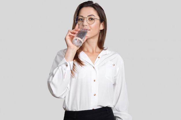 Studio shot of prosperous female entrepreneur wears round glasses