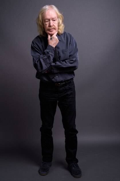 Studio shot of senior businessman with mustache against gray background