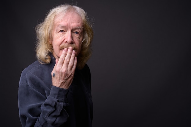 Studio shot of senior businessman with mustache against gray background