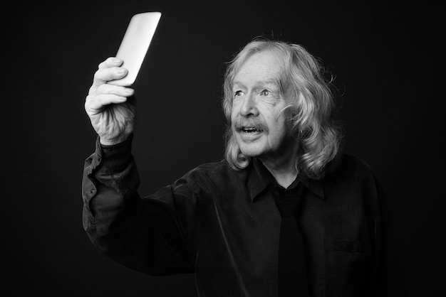 Studio shot of senior businessman with mustache against gray wall