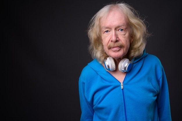 Studio shot of senior man with mustache wearing blue jacket against gray background